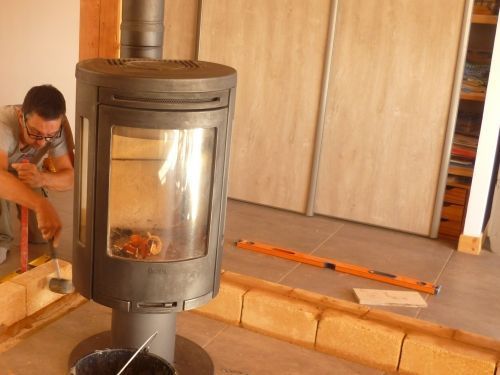 Mur  brique de terre crue derrière un poêle à bois