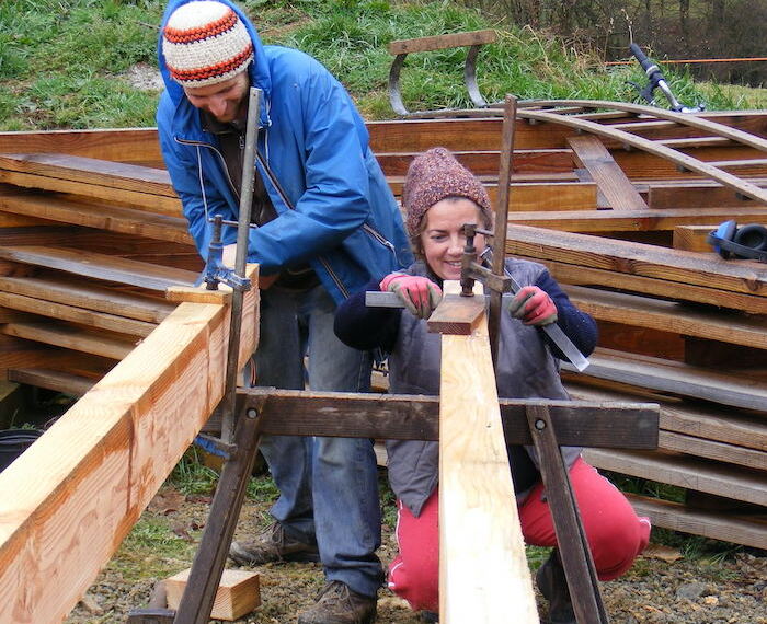 Des personnes qui fabriquent et bricolent des poutres de bois au sein d'un chantier participatif